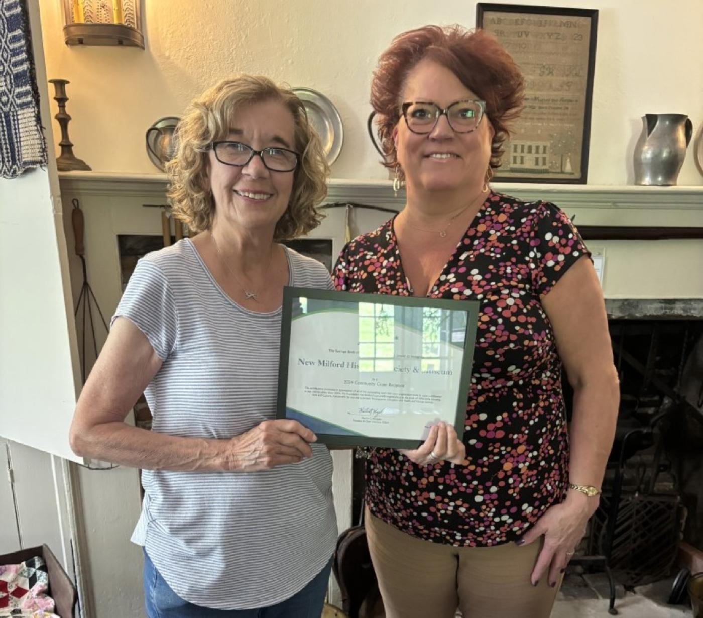 Anita Regan, board secretary at the New Milford Historical Society, accepts a community grant check 